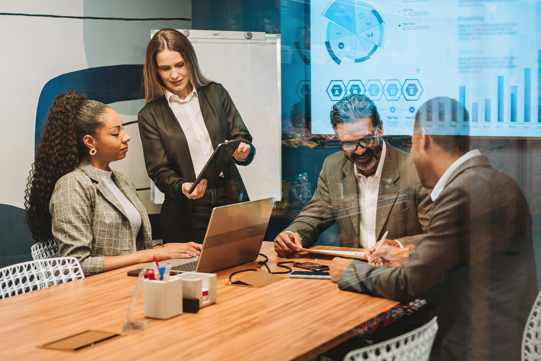Woman leading a training session with colleagues gathered around a conference table